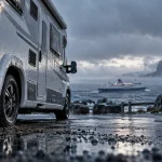 Cap Nord en camping car : camping-car sur parking côtier près du ferry et mer de Barents brumeuse